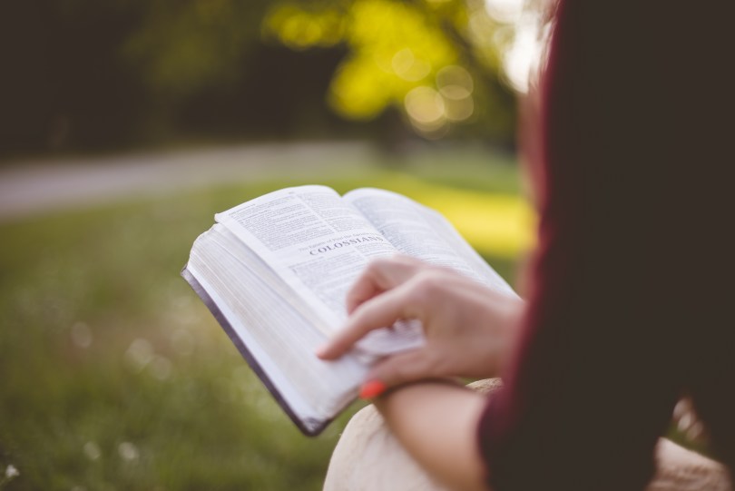 woman reading Bible in blurry natural setting